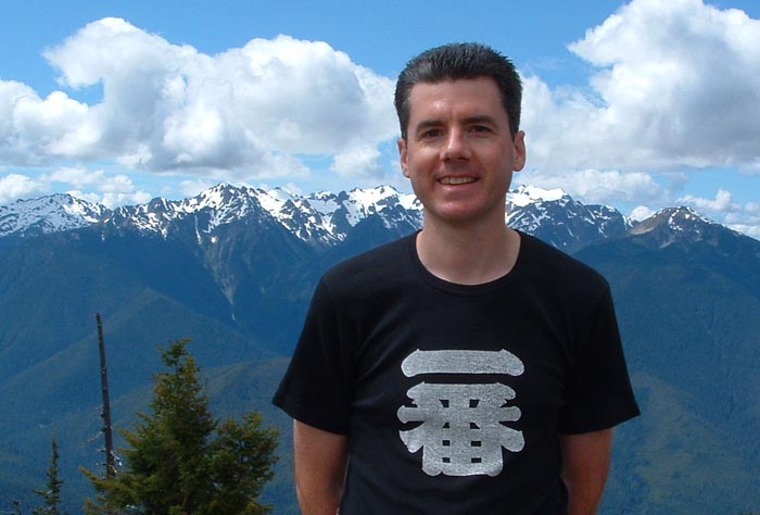photo of John Hunter with snow covered mountain peaks in the background